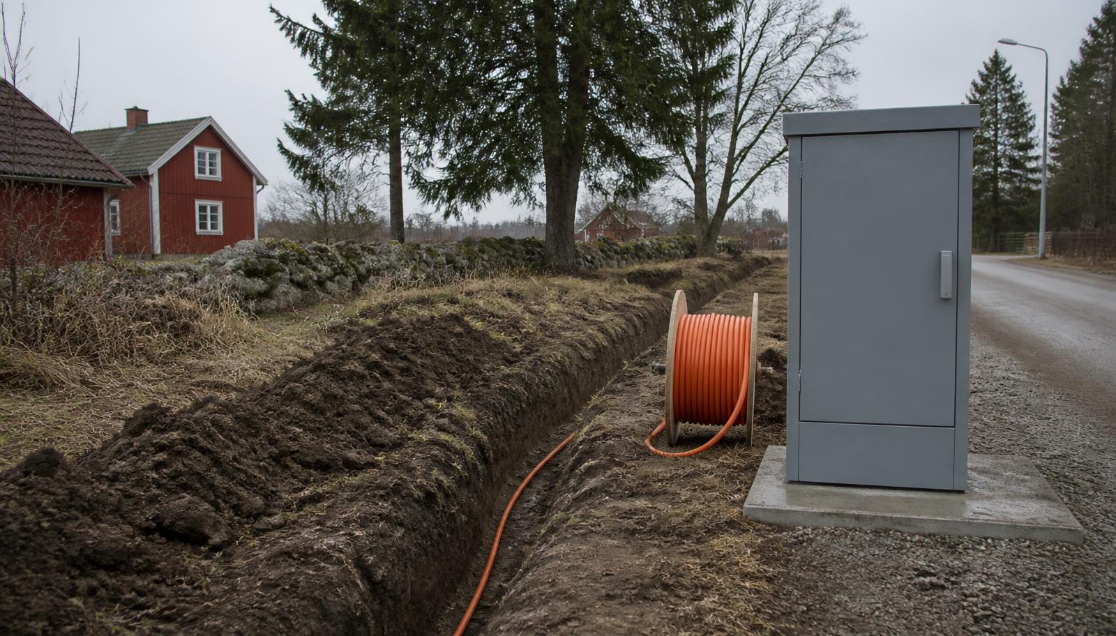 Fiberschakt med orange kabelrör och ett grått kopplingsskåp i ett svenskt villaområde